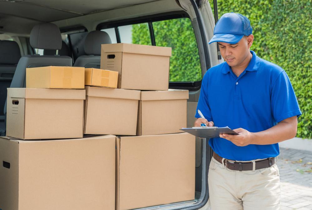 A moving truck unloading cargo with a man holding a clipboard. What steps to take after an accident with a U-Hault ruck.