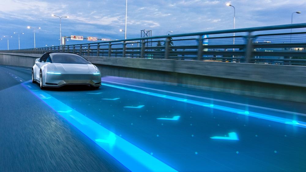 A silver autonomously driving car traveling on a freeway, leaving the owner to wonder if Tesla’s self-driving feature causes accidents.