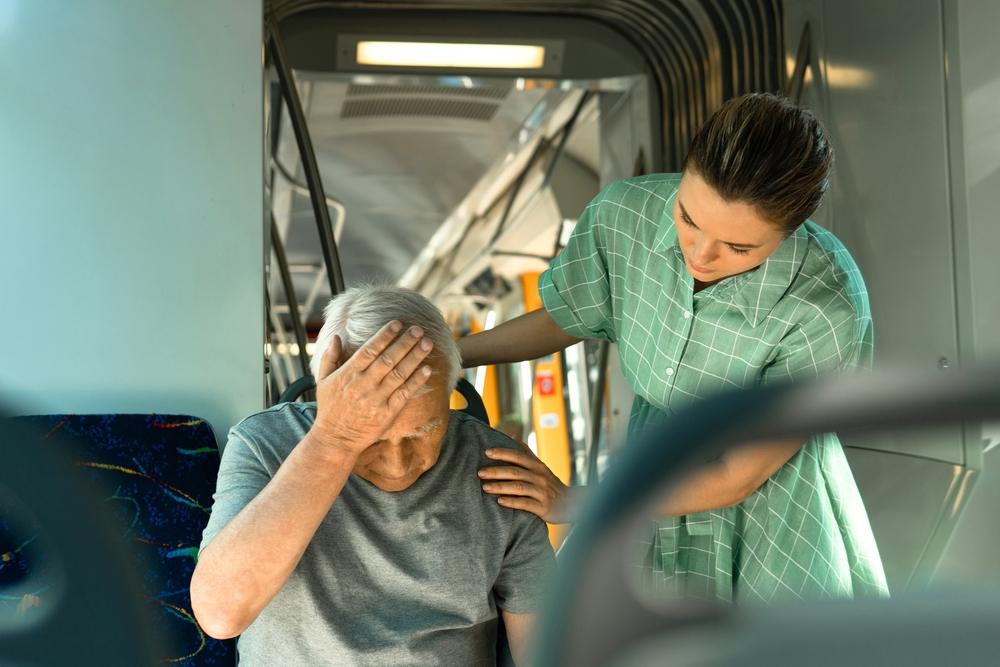 A woman consoling an older man on a city bus after it crashes, explaining what the average settlement for a bus accident injury is.