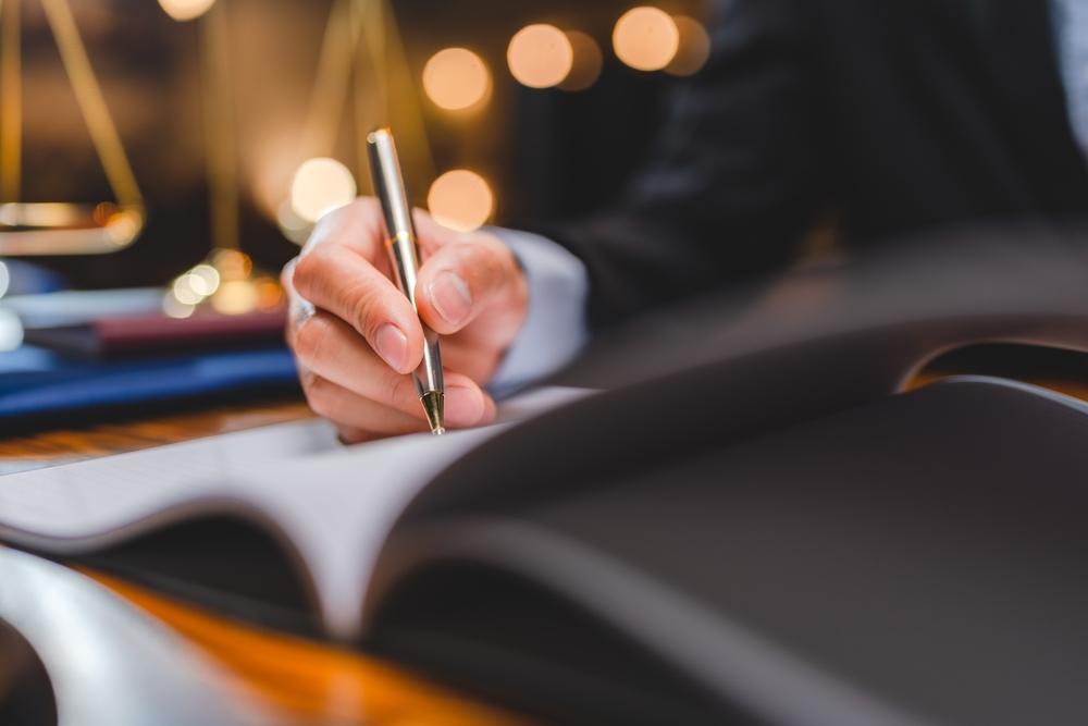 A lawyer writing in his logbook after negotiating a higher car accident settlement.