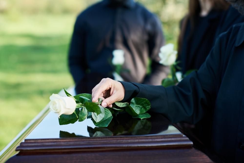 A woman placing a white rose on a coffin at a funeral. What is the wrongful death statute of limitations in Idaho?