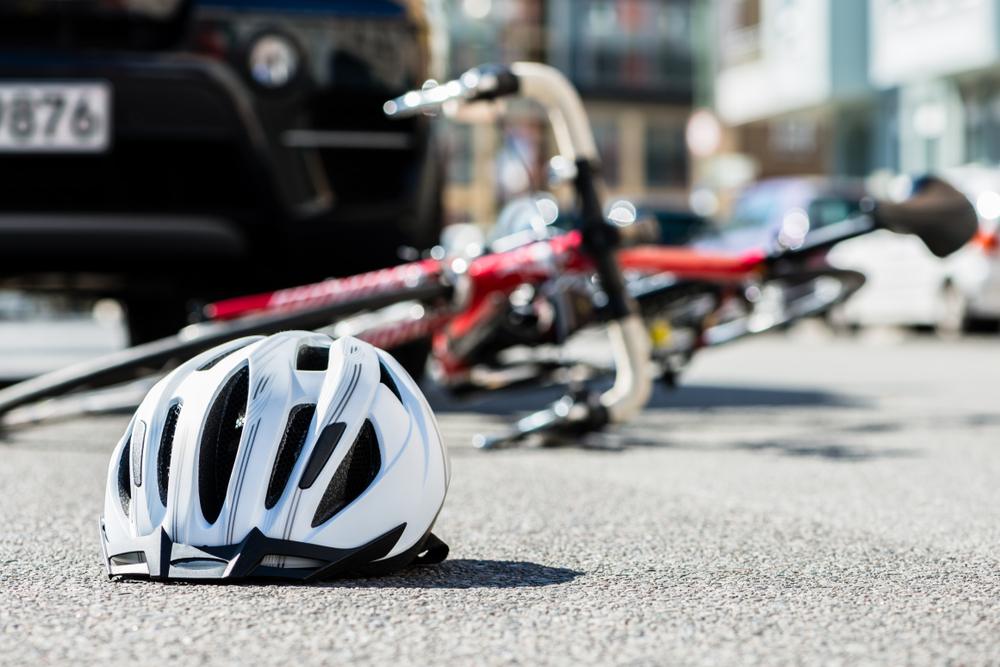 A helmet and bike on the ground after an accident. How to file a claim after a bicycle accident.