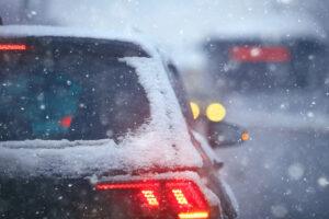 Cars sitting in highway traffic in the snow. Black ice and hydroplaning accidents: winter driving risks.