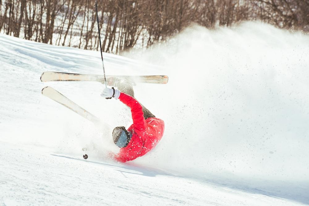 A skier falling in the snow. What to do if you’re injured in a skiing accident.