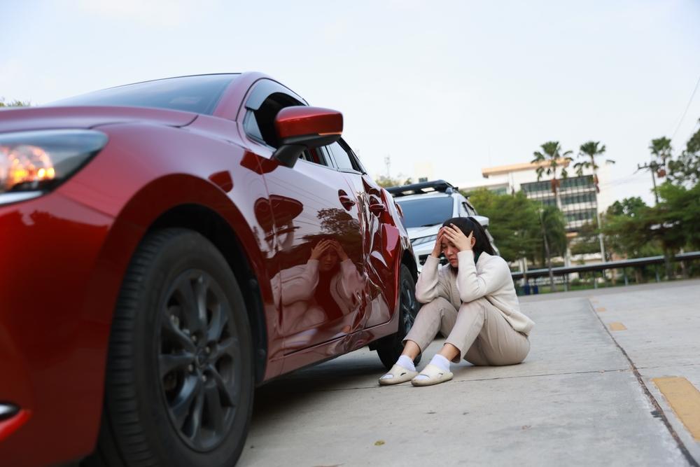 An upset woman evaluating the damage to her car after a car crash. How to get a car crash report in West Valley City, UT?
