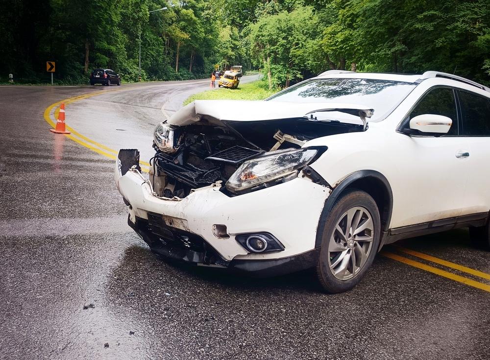 A white car in the middle of the street, damaged from a car accident. Does PIP cover lost wages after a Utah car accident?