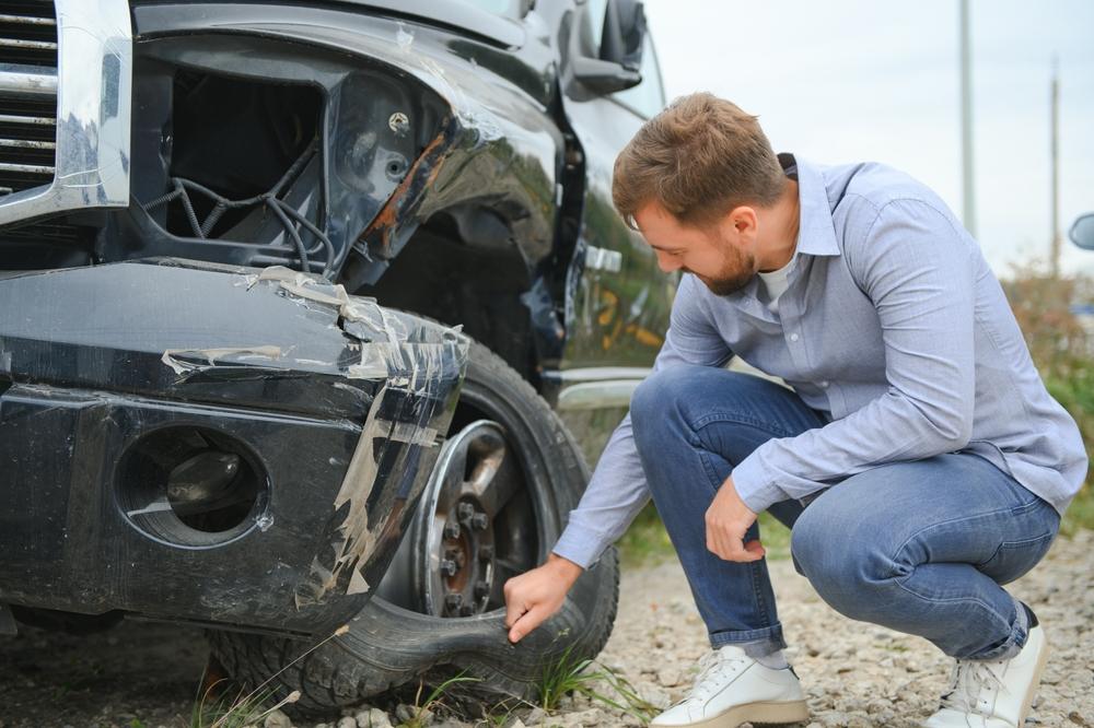 A man checking the damage after a car crash. Is Idaho a no-fault state?