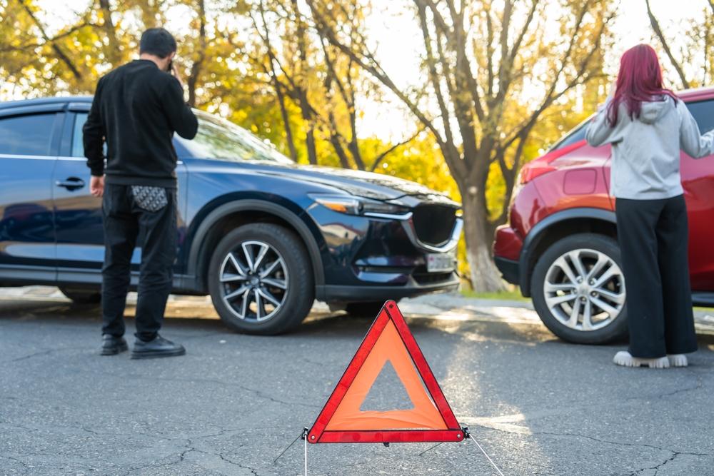 Two car accident victims standing outside of their cars. Are car accident settlements taxable in Washington?