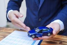 An accountant holding a model car while writing on a document. Are car accident settlements taxable in Idaho?