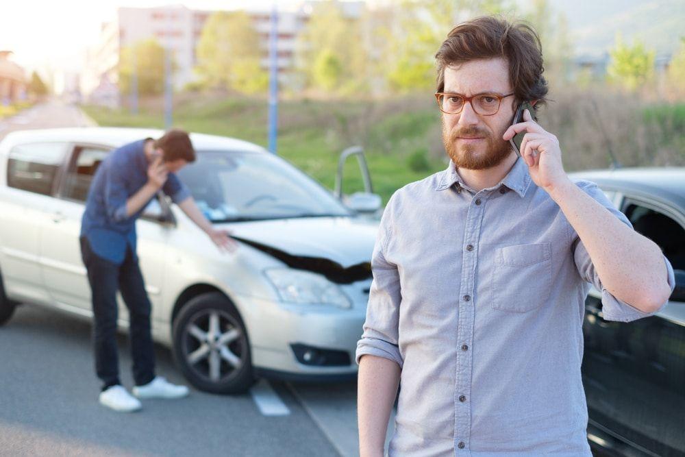 A man on the phone in front of a car accident. How long does a car accident stay on your record?