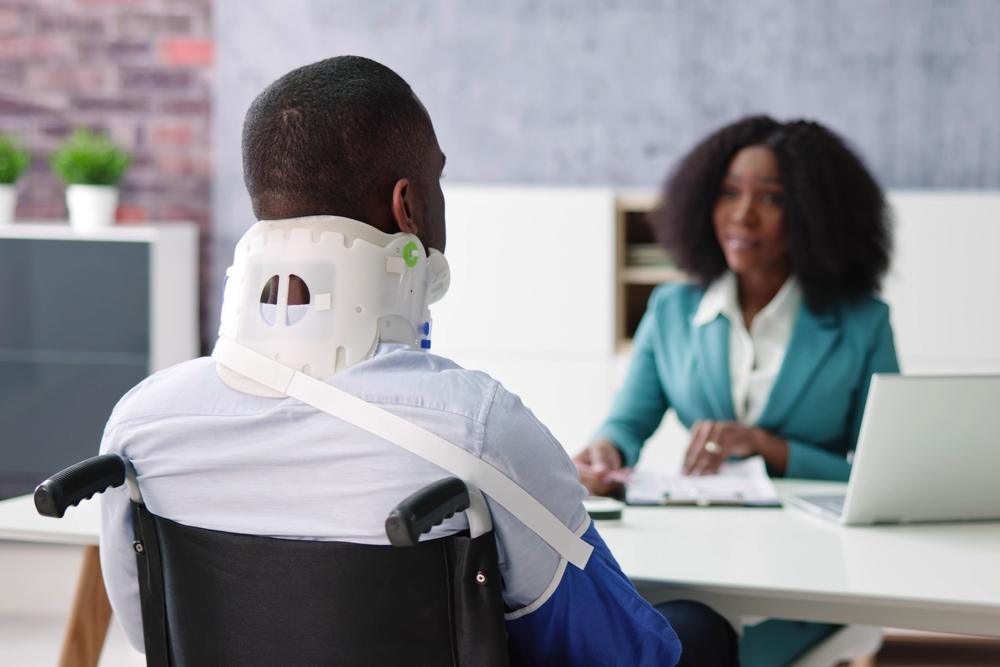An injured man in a neck brace and sling speaking with a motorcycle accident lawyer. How to find the best car accident lawyer.