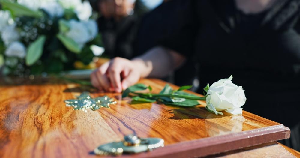 A woman placing a white rose on a coffin. What is a wrongful death lawsuit?